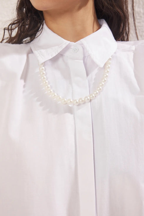 قميص أبيض بتفاصيل من اللؤلؤ